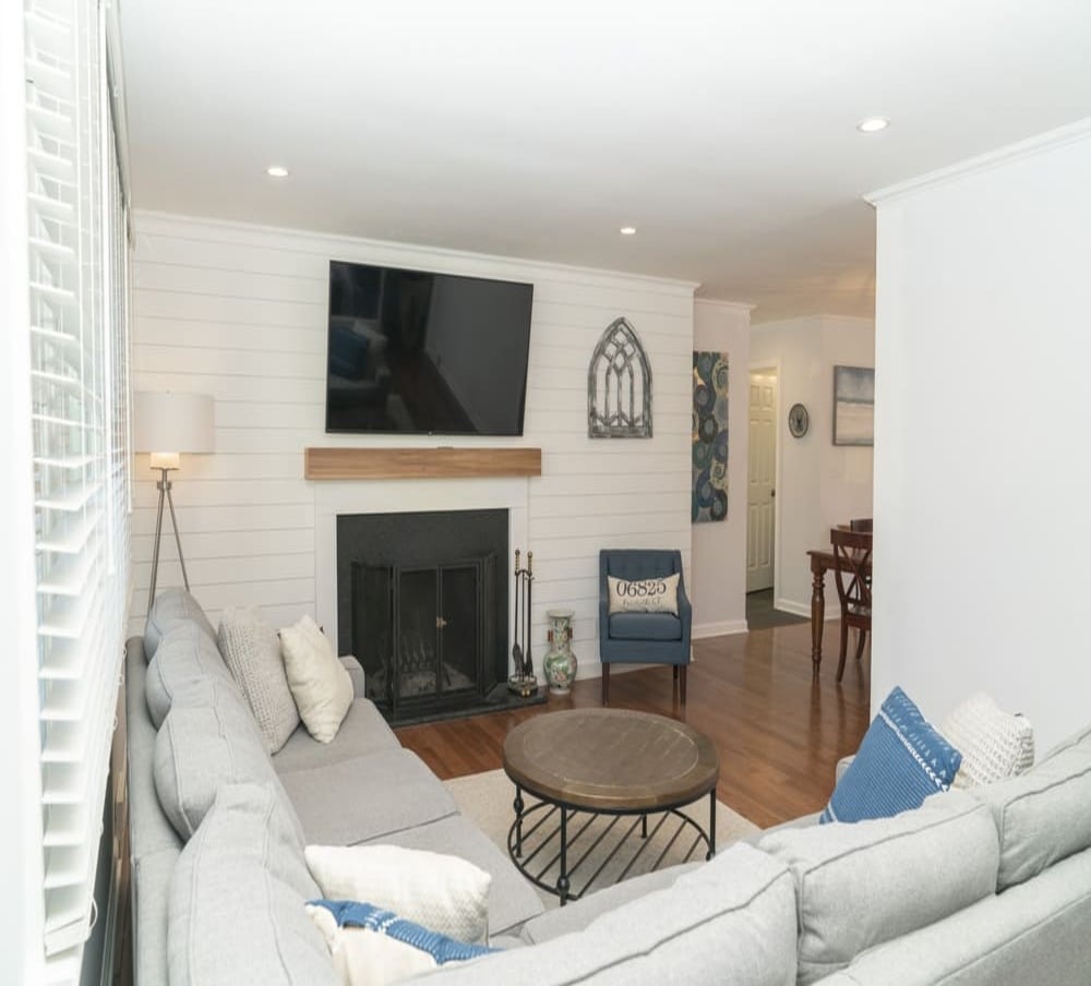 living rea with white couch and flat screen mounted tv above fireplace by raymond design builders